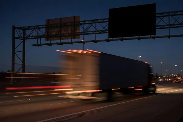 Illustration: a tractor-trailer on an interstate at night.